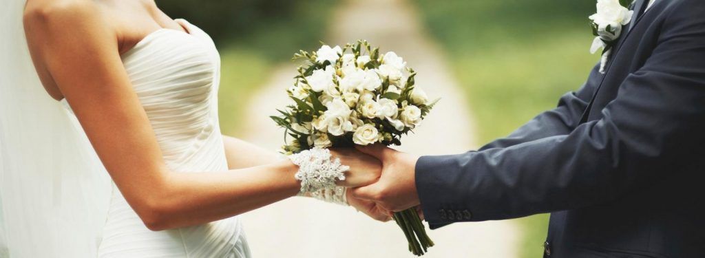 Novios entregándose un ramo de flores blancas